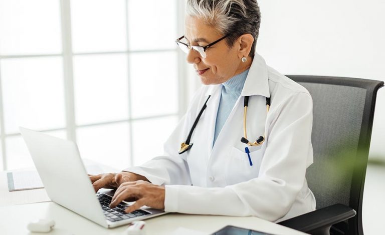 Healthcare professional enters medical record data on a computer in a modern healthcare workspace.