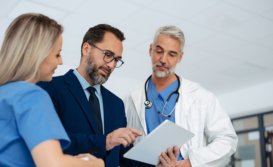 Medical and administrative staff work together to analyze revenue cycle information on a tablet.