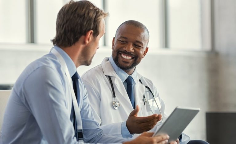 Healthcare professional explaining information to a man in a bright office setting.